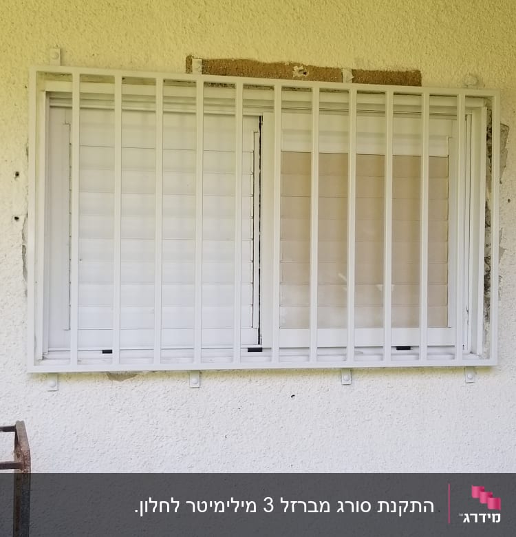 חלון עם סורגים לבנים על קיר חיצוני